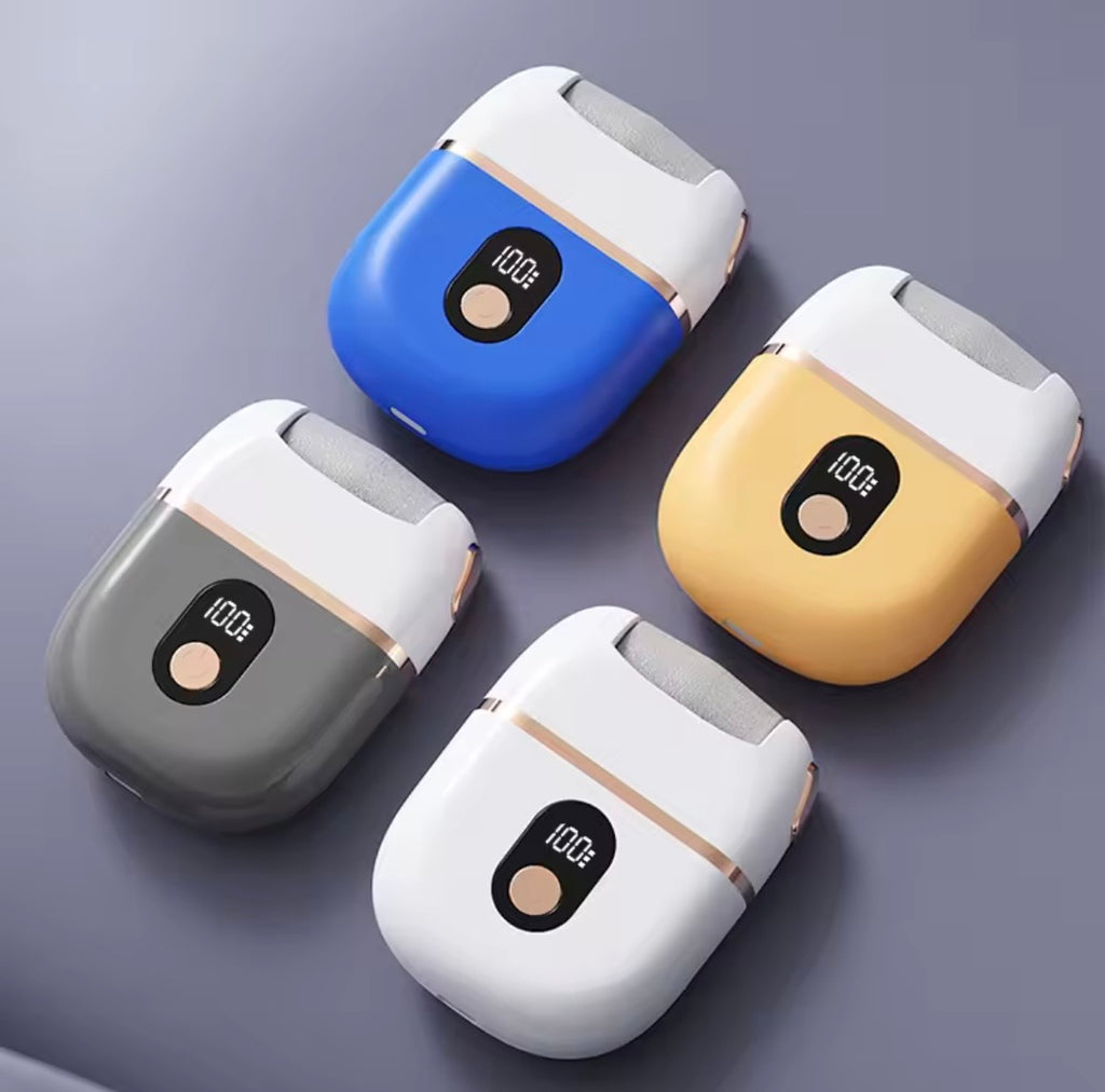 Four electric foot files shown in different color combinations (blue/white, gray/white, yellow/white, and white/white) arranged diagonally on a dark gray surface.